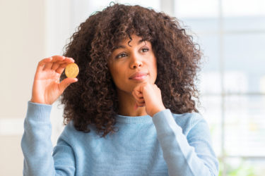 African american woman holding golden bitcoin cryptocurrency at home serious face thinking about question, very confused idea